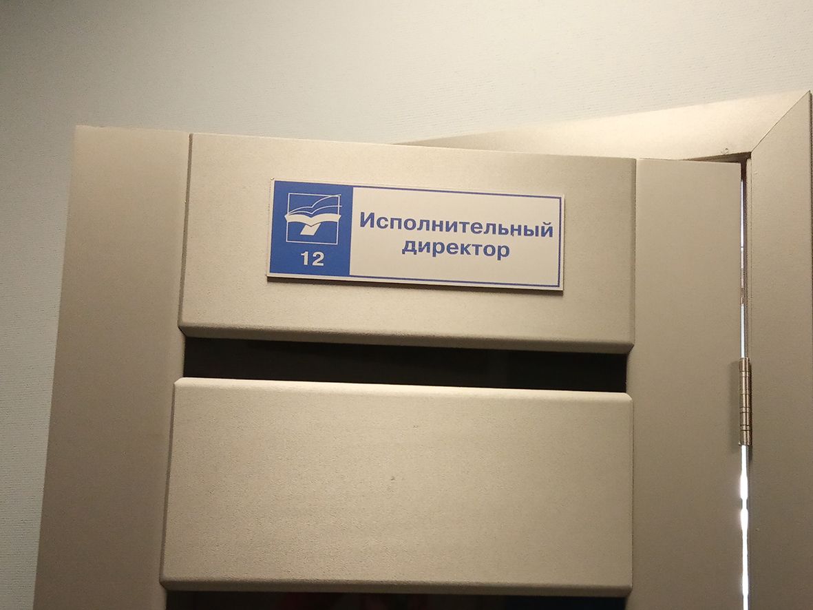 Табличка «Исполнительный директор» с номером 12 в верхней части офисной двери